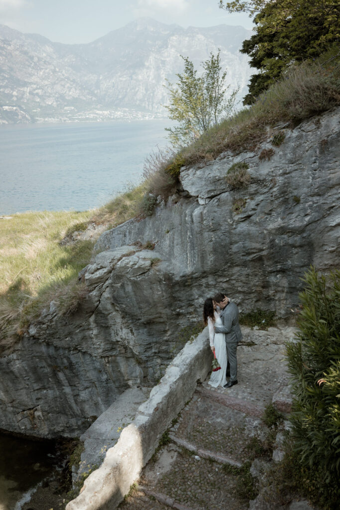 Couple kissing on a cliffside path by Lake Garda during their Malcesine elopement