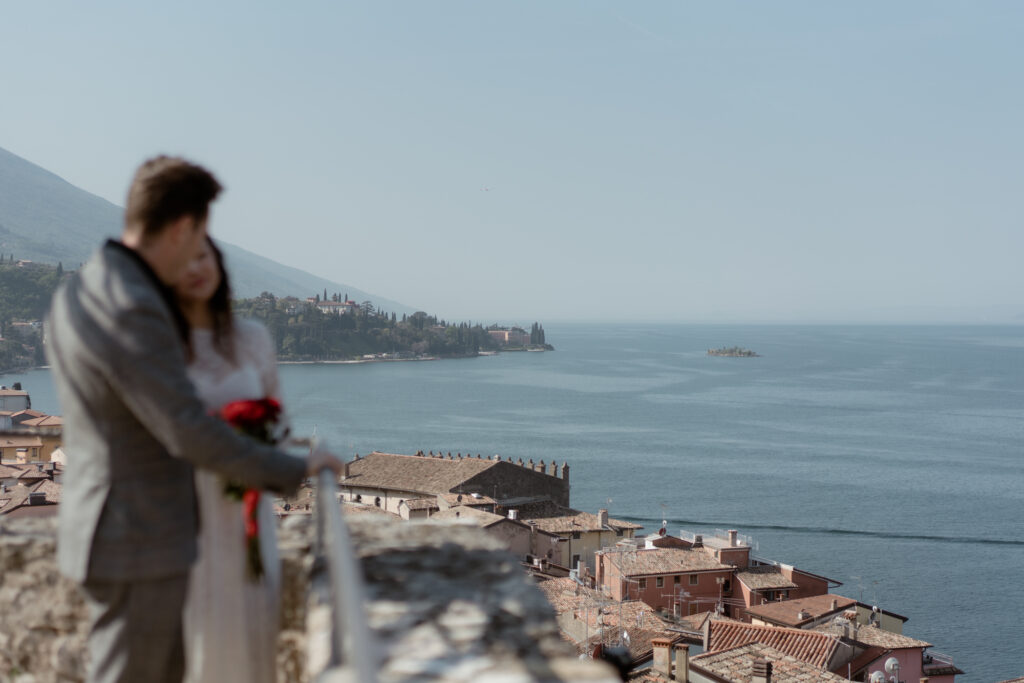 Couple on a castle terrace in Malcesine with Lake Garda and the old town below