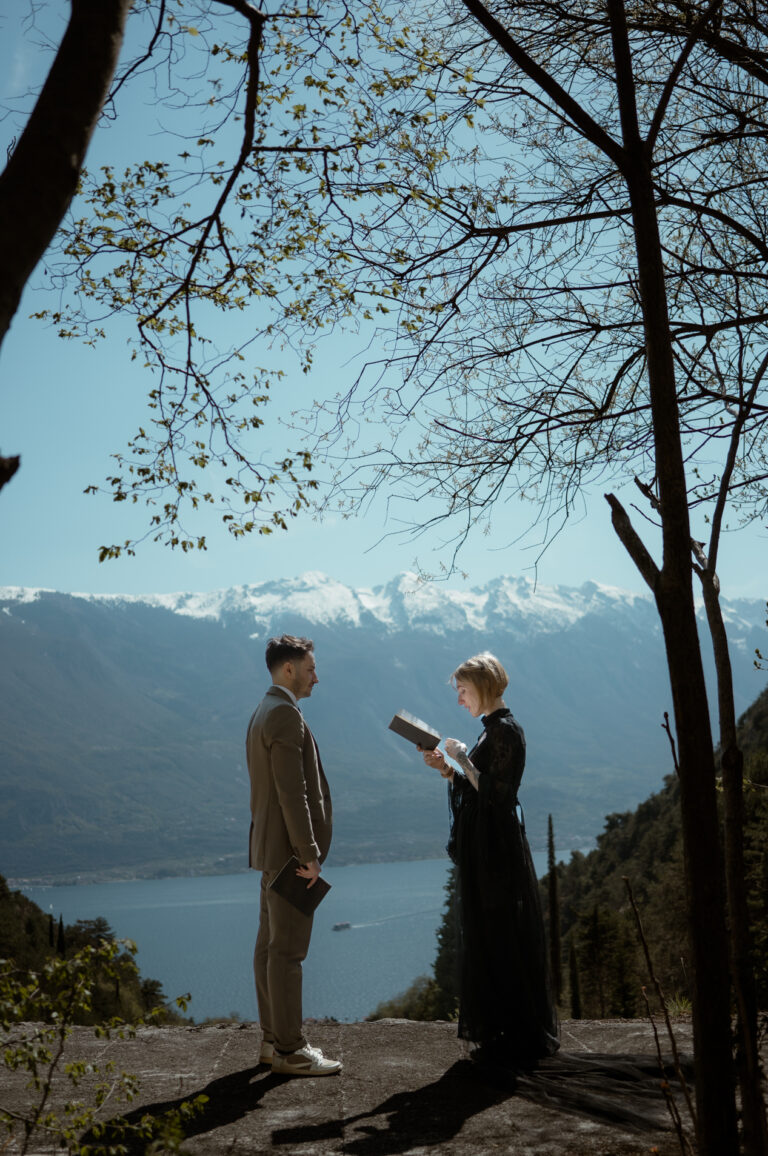 Couple reading vows during their Limone del Garda elopement with Lake Garda and snowy mountains behind them
