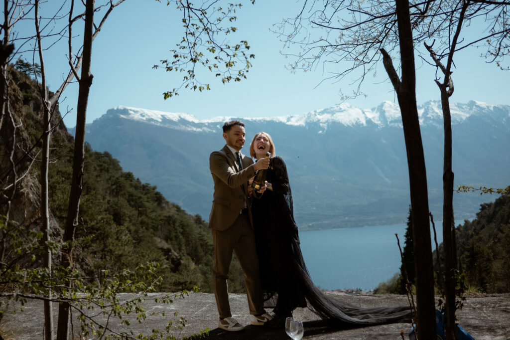 Couple celebrating with champagne during their Limone del Garda elopement overlooking Lake Garda