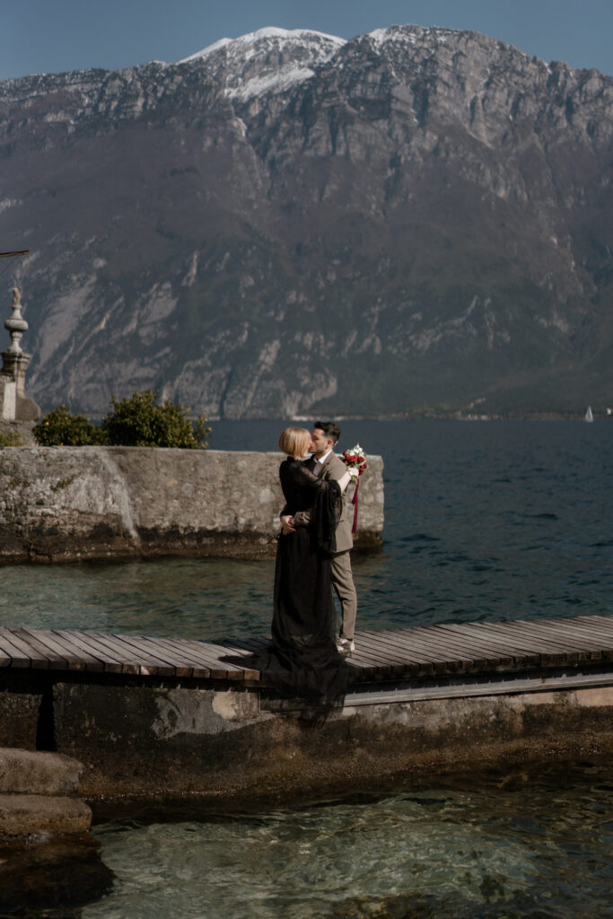 Couple embracing on a dock by Lake Garda during their Limone del Garda elopement