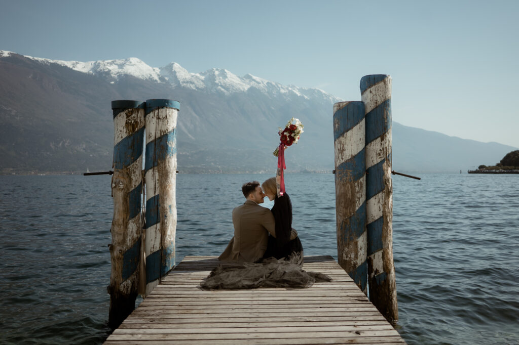 Couple sitting together on a wooden dock in Limone del Garda during their Lake Garda elopement