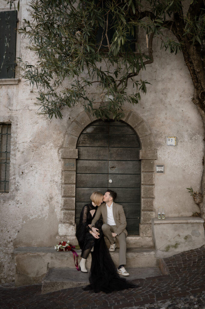 Couple sitting by an old doorway during their Limone del Garda elopement in Italy