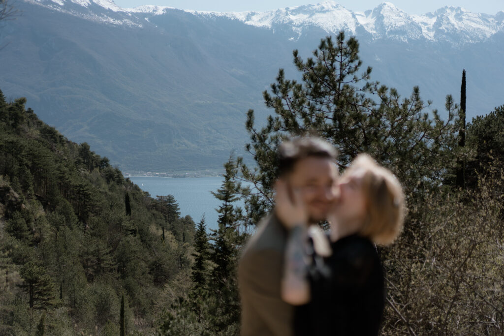 Couple kissing with Lake Garda and snowy mountains in the background during their Limone del Garda elopement