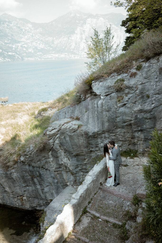 Couple kissing on a cliffside path by Lake Garda during their Malcesine elopement