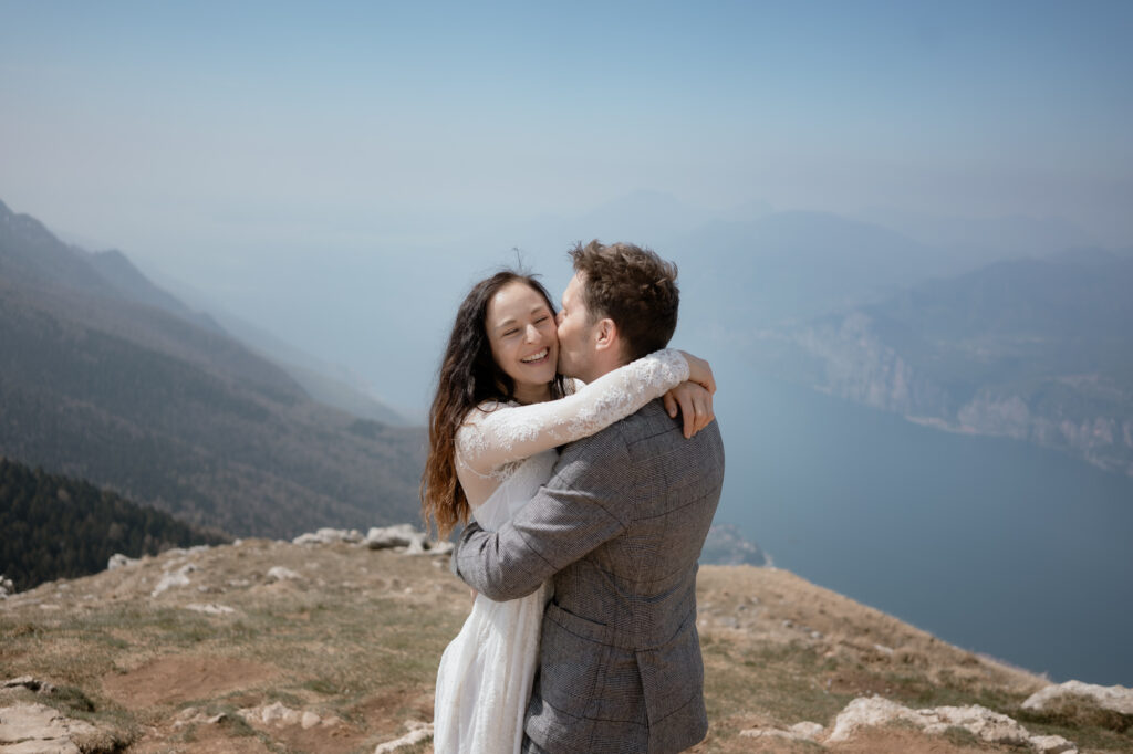 Couple embracing on Monte Baldo with Lake Garda behind them during their Malcesine elopement