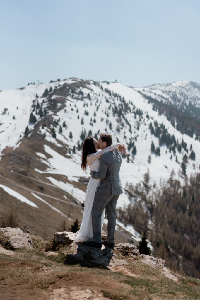 Couple kissing on Monte Baldo with snowy mountains during their Malcesine Lake Garda elopement