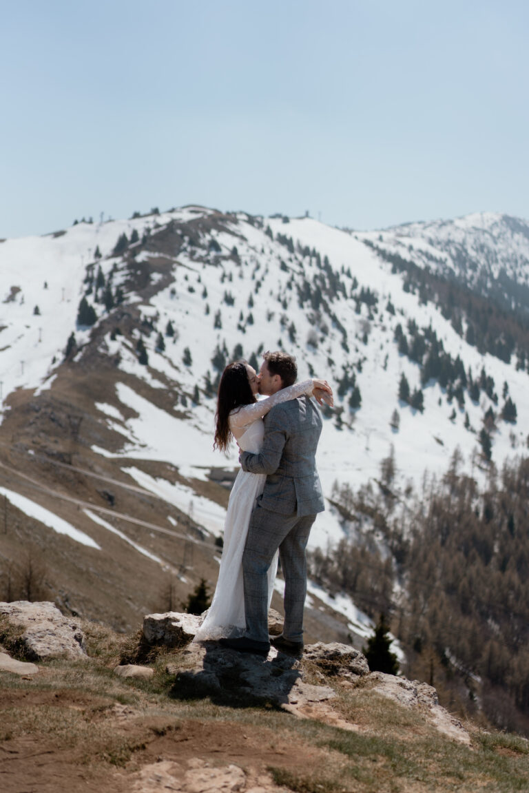 Couple kissing on Monte Baldo with snowy mountains during their Malcesine Lake Garda elopement