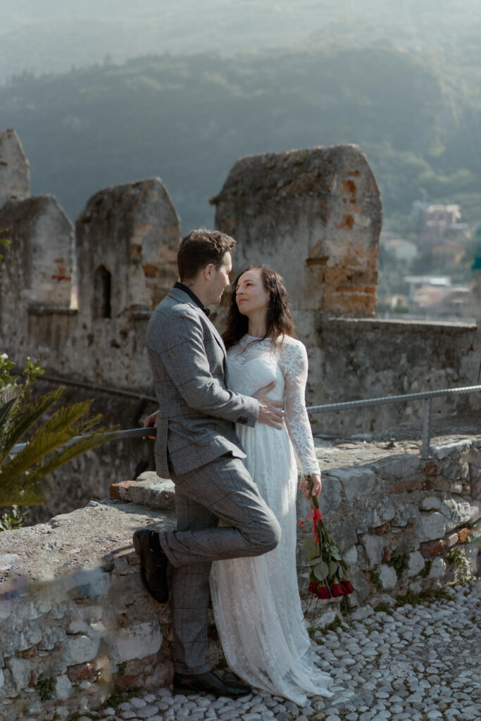 Couple embracing by the castle walls during their Malcesine Lake Garda elopement