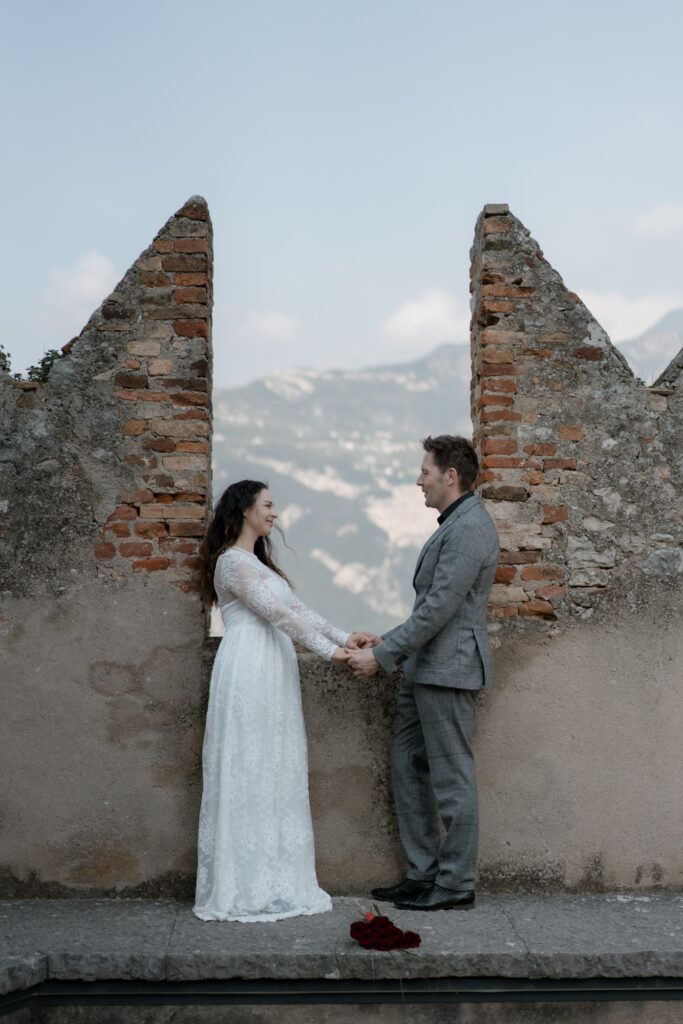 Couple holding hands by the castle walls during their Malcesine Lake Garda elopement