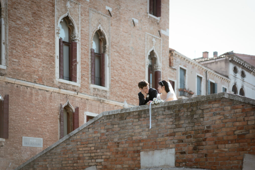 Couple sitting together on a brick bridge during their Venice elopement in Italy