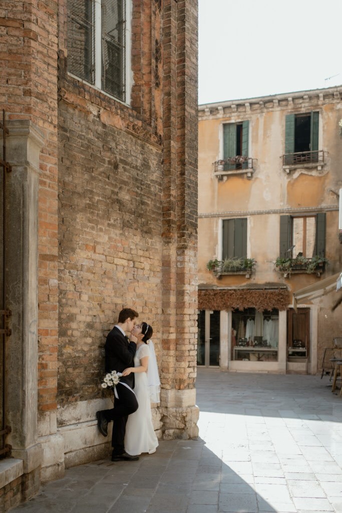 Couple kissing beside a brick wall during their Venice elopement portraits