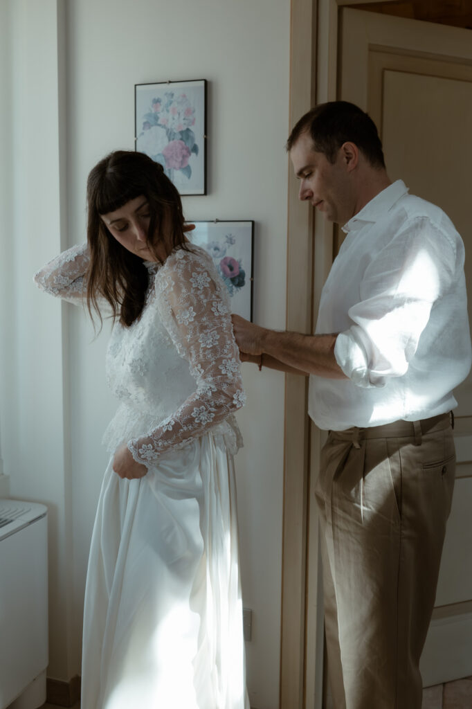 Groom helping the bride get ready before their Monte Isola elopement on Lake Iseo