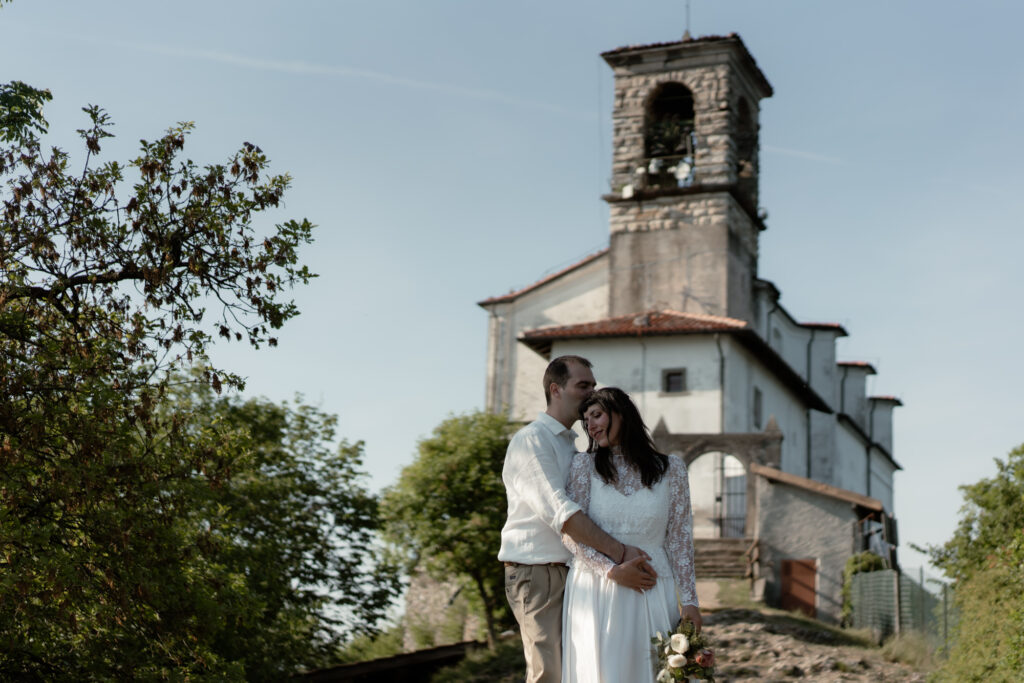 Couple standing together by a church during their Monte Isola elopement on Lake Iseo