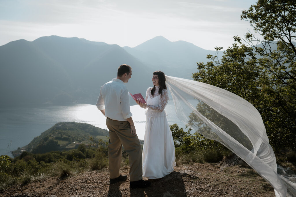 Couple exchanging vows on Monte Isola with a flowing veil and Lake Iseo behind them
