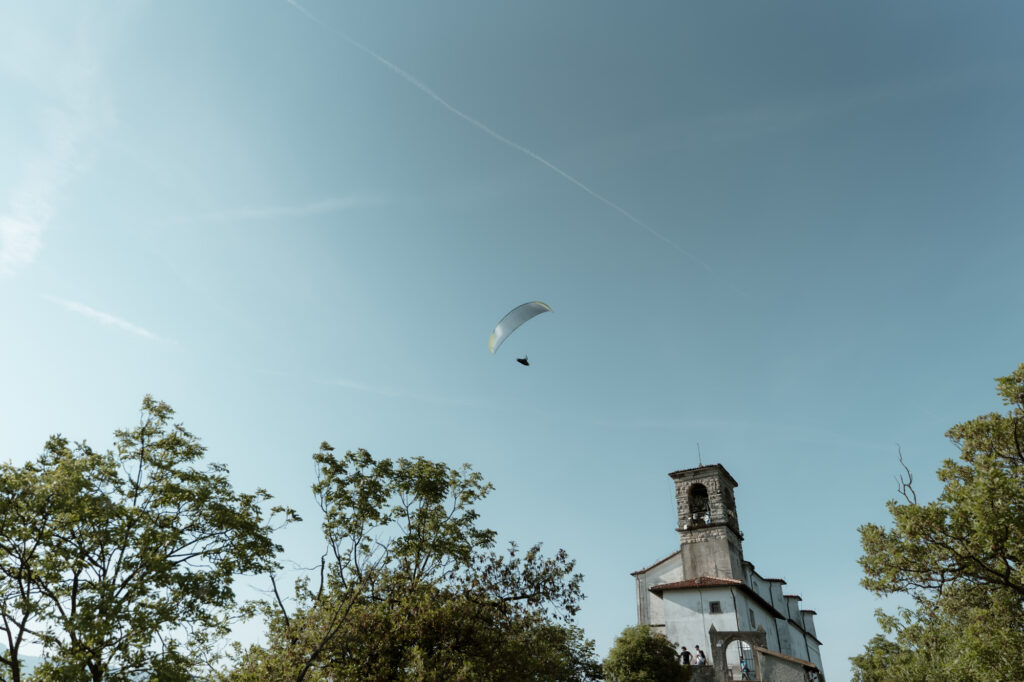 Church on Monte Isola with a paraglider above Lake Iseo during an elopement day in Italy
