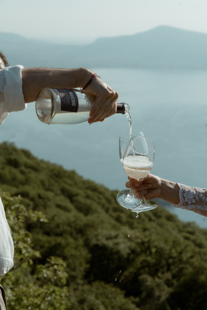 Couple pouring wine above Lake Iseo during their Monte Isola elopement in Italy