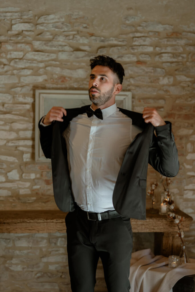 Groom putting on his jacket before an intimate wedding at a countryside villa in Italy