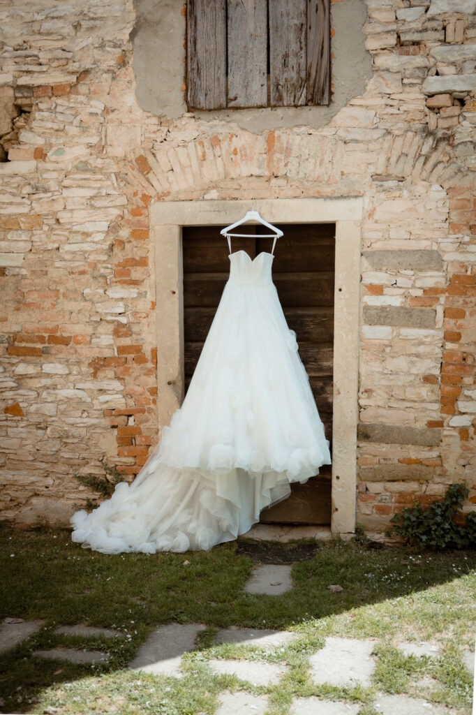 Wedding dress hanging on an old wooden door at a countryside villa in Italy
