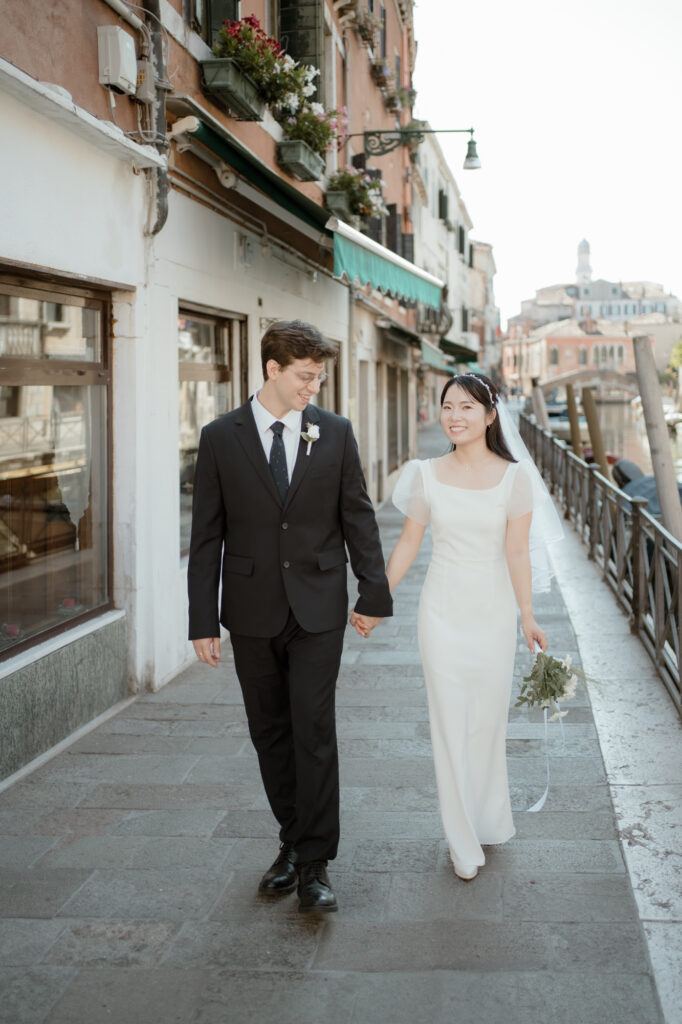 Couple walking hand in hand beside a canal during their Venice elopement