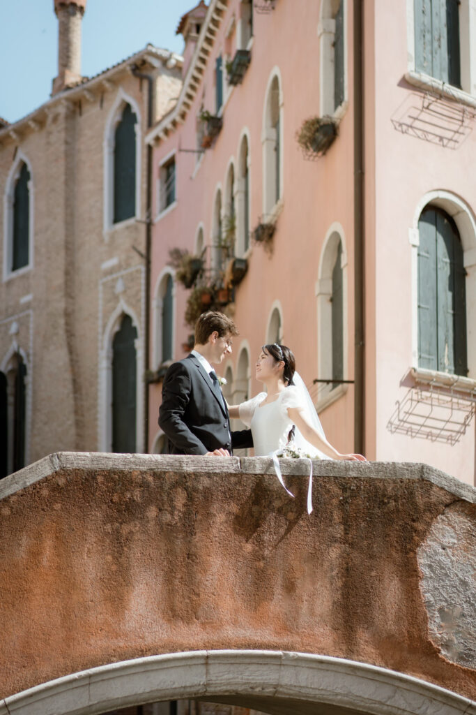 Couple standing together on a pastel bridge during their Venice elopement