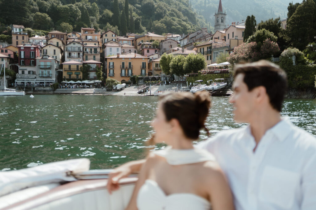 Couple on a boat looking toward Varenna during a Lake Como elopement session in Italy