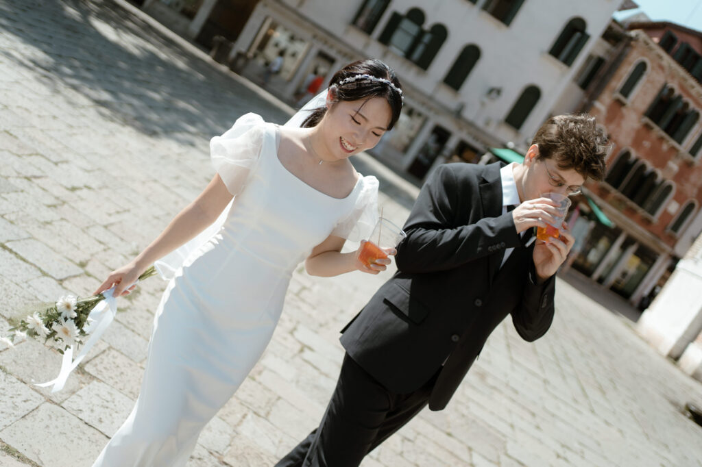 Couple walking through Venice with spritz during their elopement day in Italy