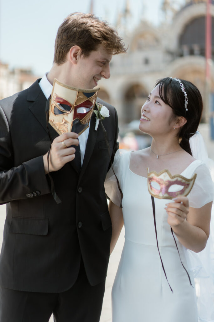 Couple holding Venetian masks during their Venice elopement in Italy